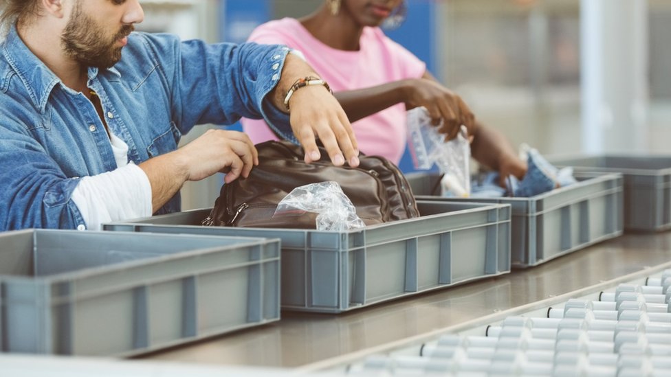 Pasajeros separan una bolsa plástica de su equipaje de mano al pasar por seguridad