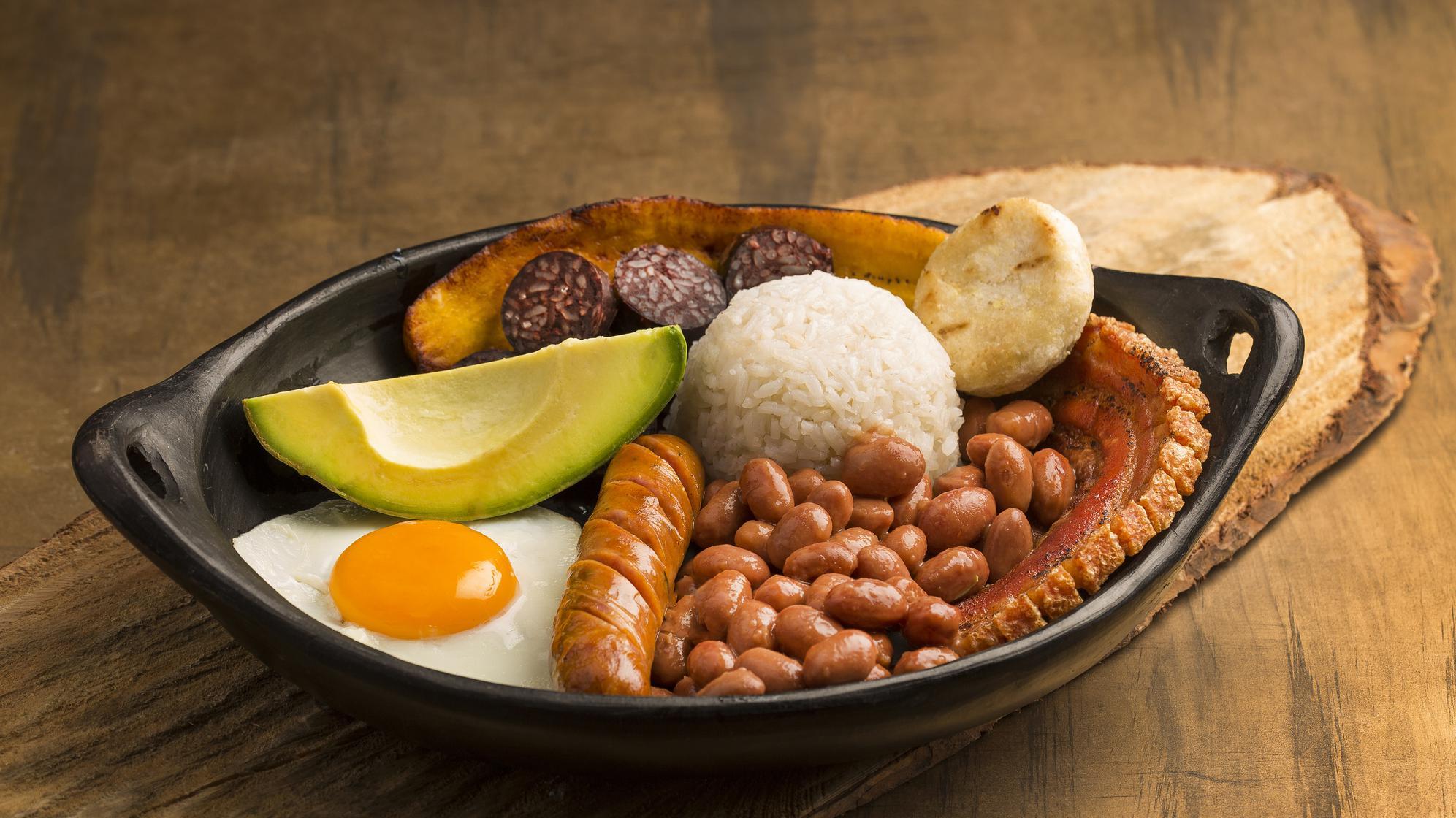 Bandeja con fríjoles, huevo, arroz, salchicha, aguacate, chicharrón y arepa