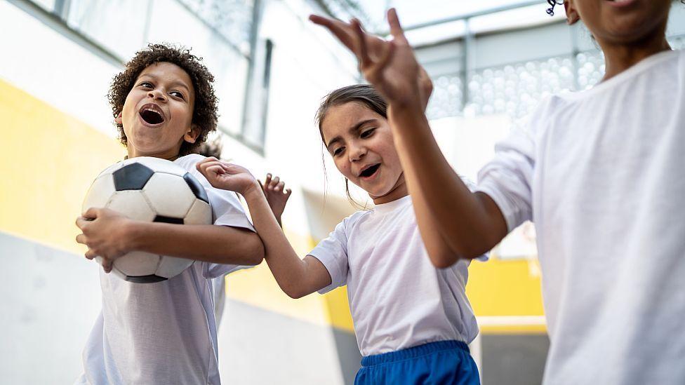 Niños jugando al fútbol en la escuela