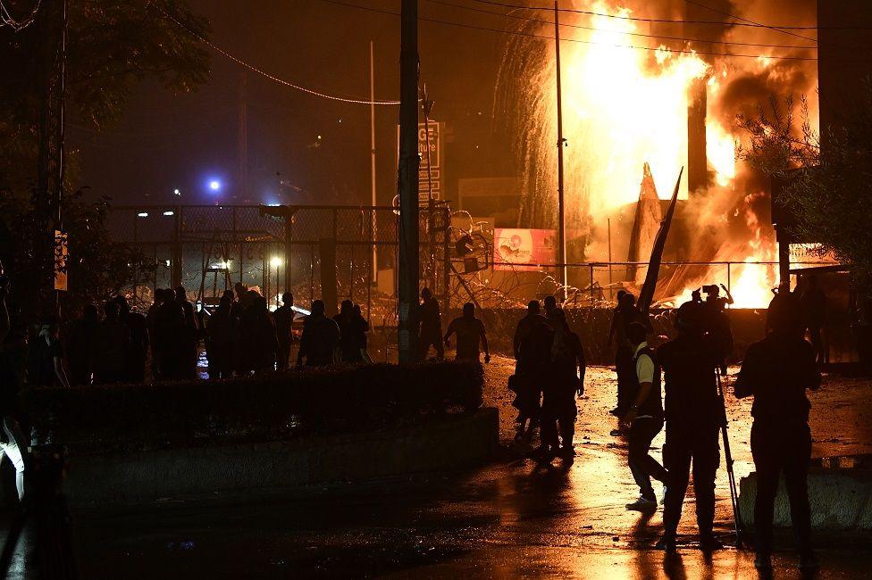 Manifestantes al frente de una zona con un incendio