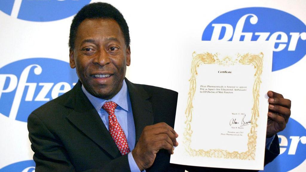 La leyenda del fútbol brasileño Pelé muestra un certificado como primer embajador educativo de Japón para la disminución de la disfunción eréctil durante una conferencia de prensa en Tokio en marzo de 2002 para promover una campaña de concientización contra la impotencia.