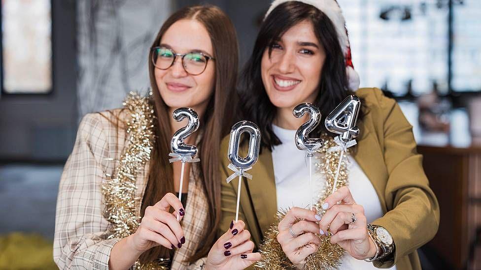 Dos jóvenes celebrando con el número 2024