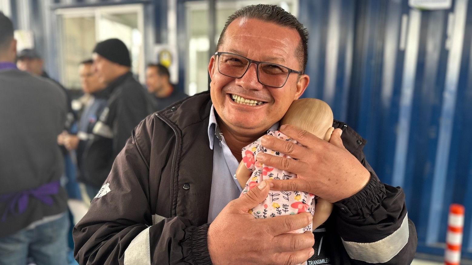 Segundo Vargas, sonriente mientras arrulla a uno de los bebés hiperrealistas de la clase. 