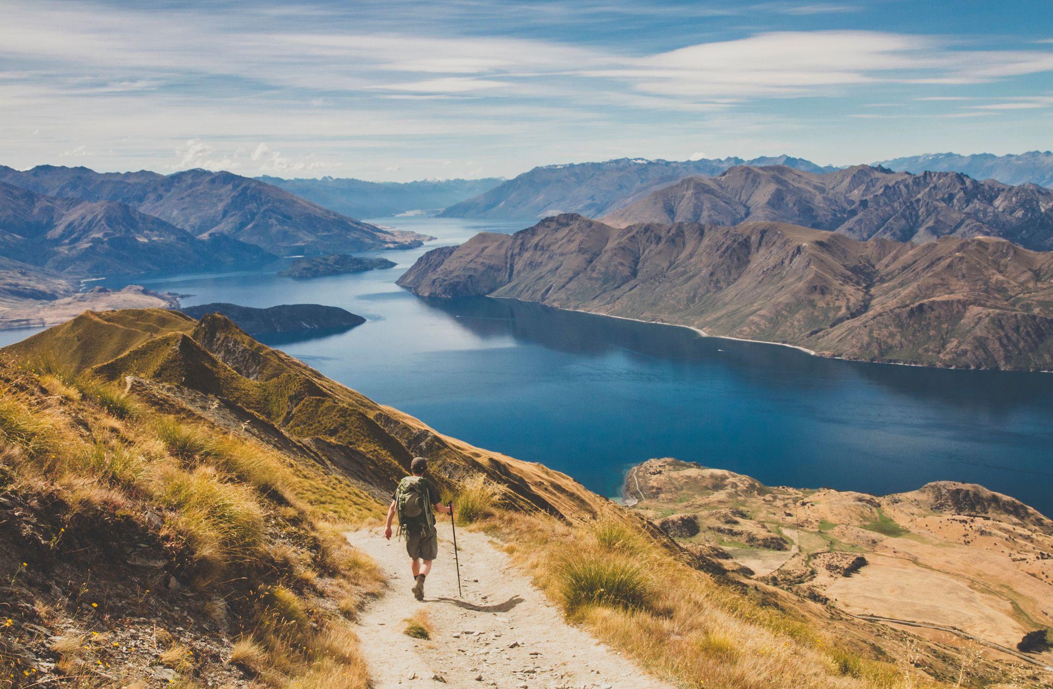 Un hombre caminando entre las montañas de Nueva Zelanda hasta un lago