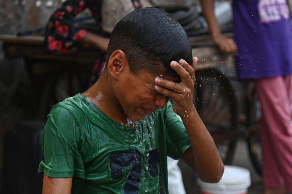 Un niño se moja en agua para aliviar el calor