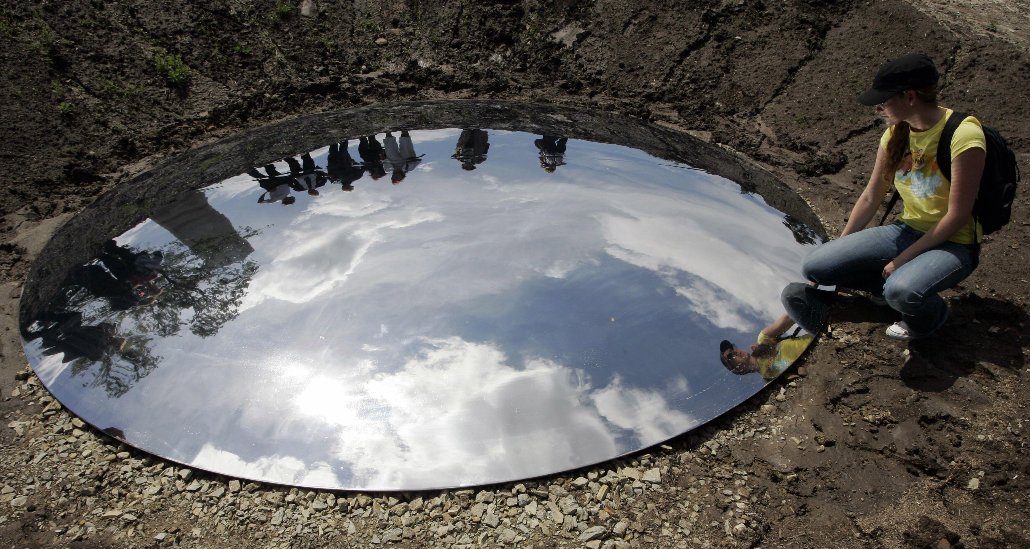 Espejo circular en suelo con cielo reflejado