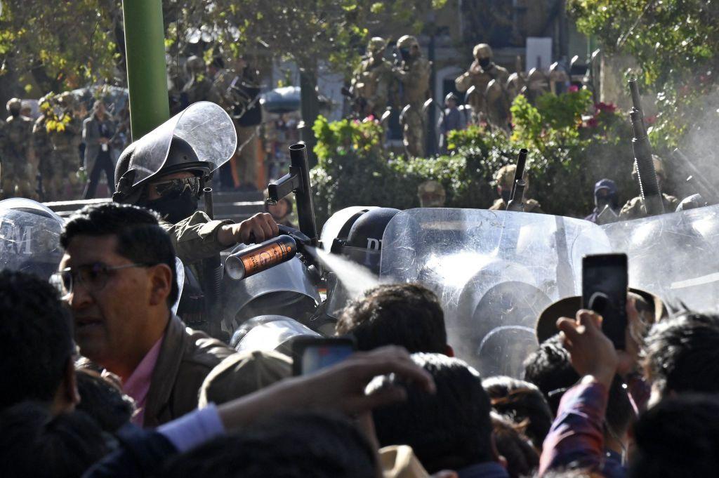 Agente lanzando gas sobre la multitud.