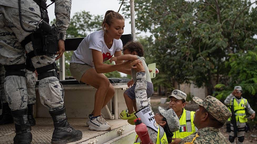 Militares ayudando a una madre y su niño a subir a una cambioneta en Tulum