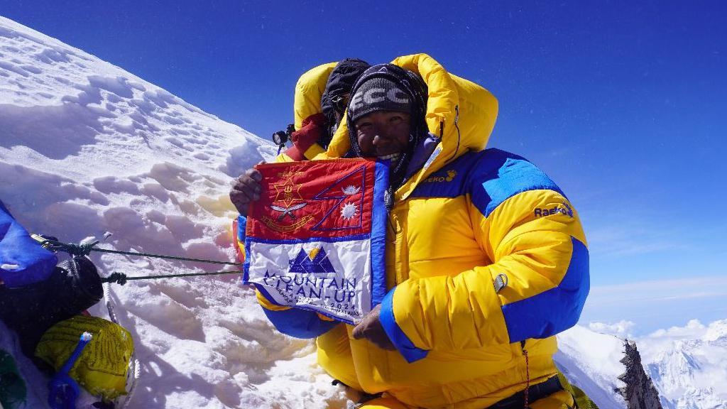 Tshiring Jangbu Sherpa muestra la bandera de la operación de limpieza de las montañas. 