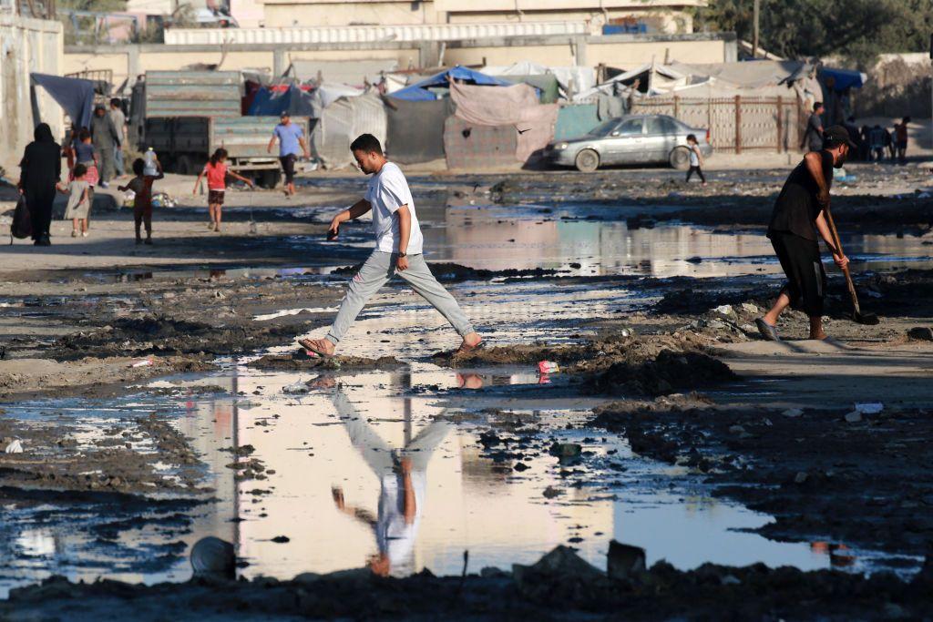 Un hombre cruza un charco de agua residual.