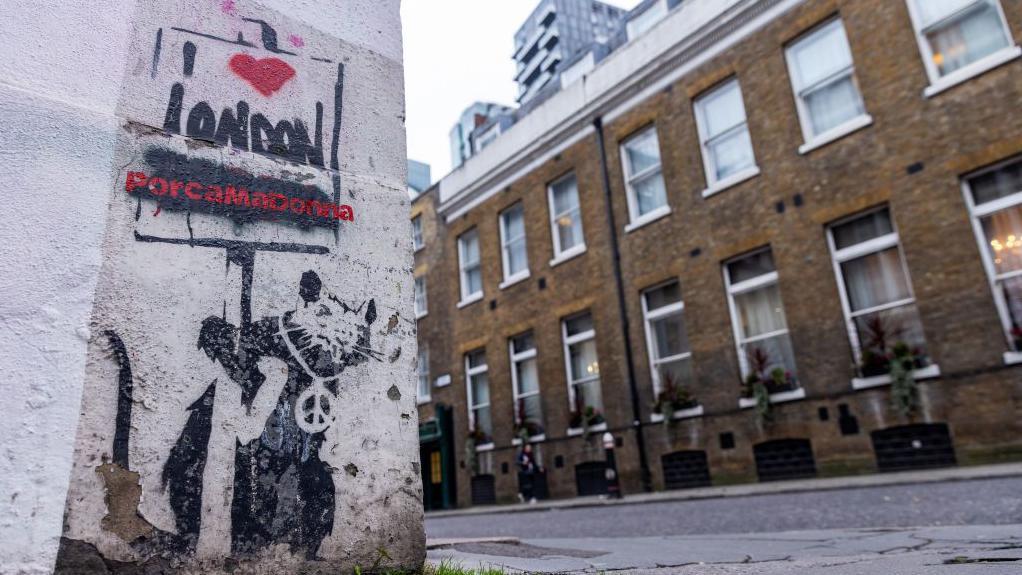 Obra de Banksy con una rata sosteniendo un cartel, fotografiada en dicienbre de 2023 en Londres 