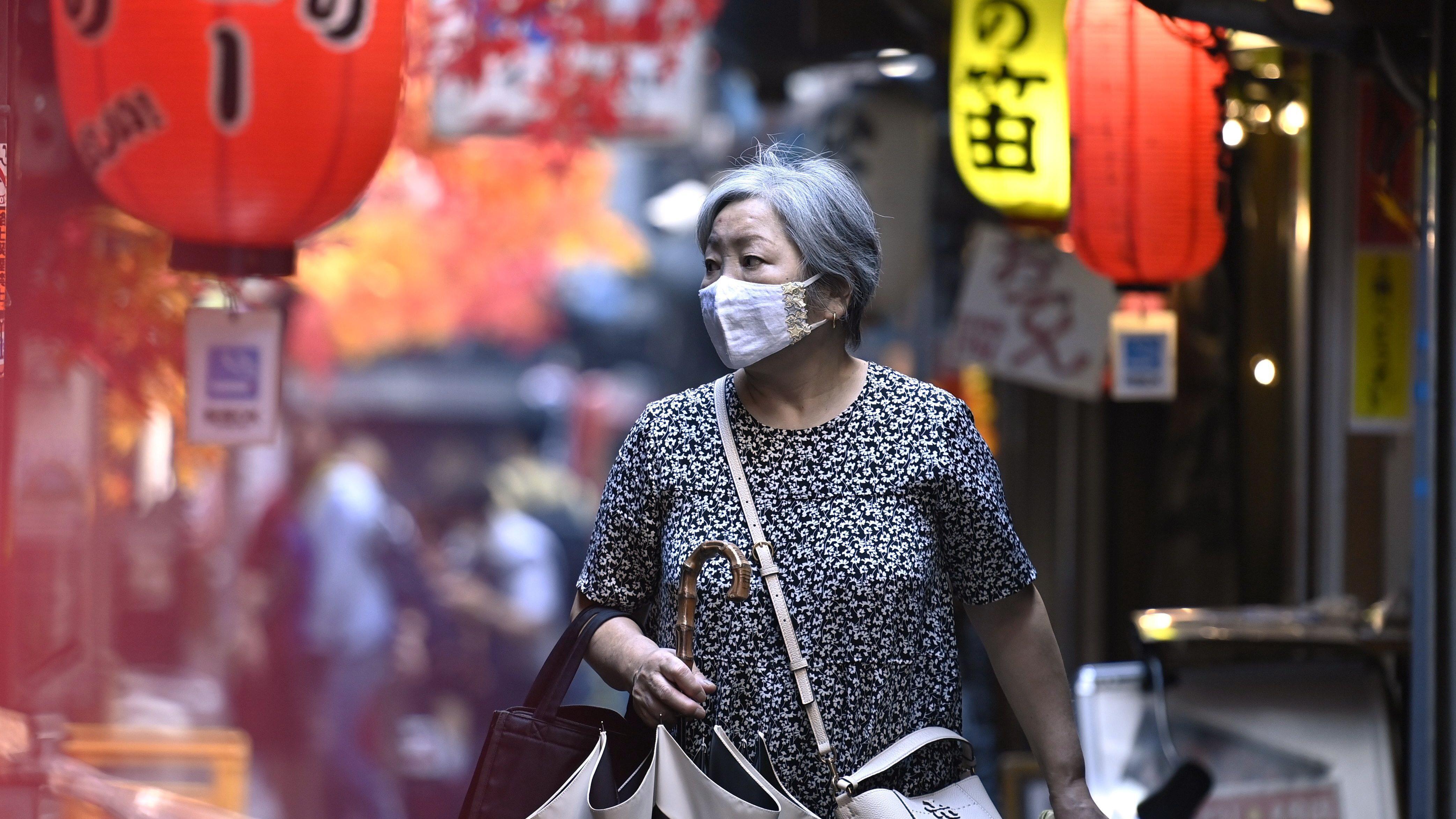 Mujer con canas camina por una calle de Tokio.