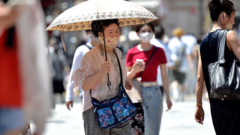 Una persona mayor camina por la calle usando un paraguas para protegerse del sol el 27 de junio de 2022, en el popular distrito de Shibuya en Tokio, Japón.