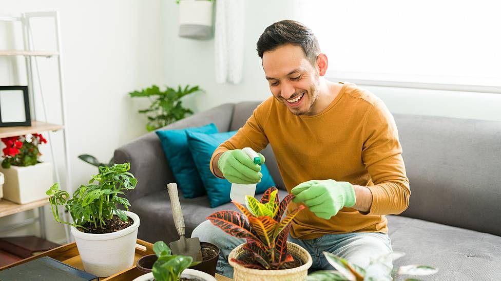 Hombre sonriendo mientras riega sus plantas