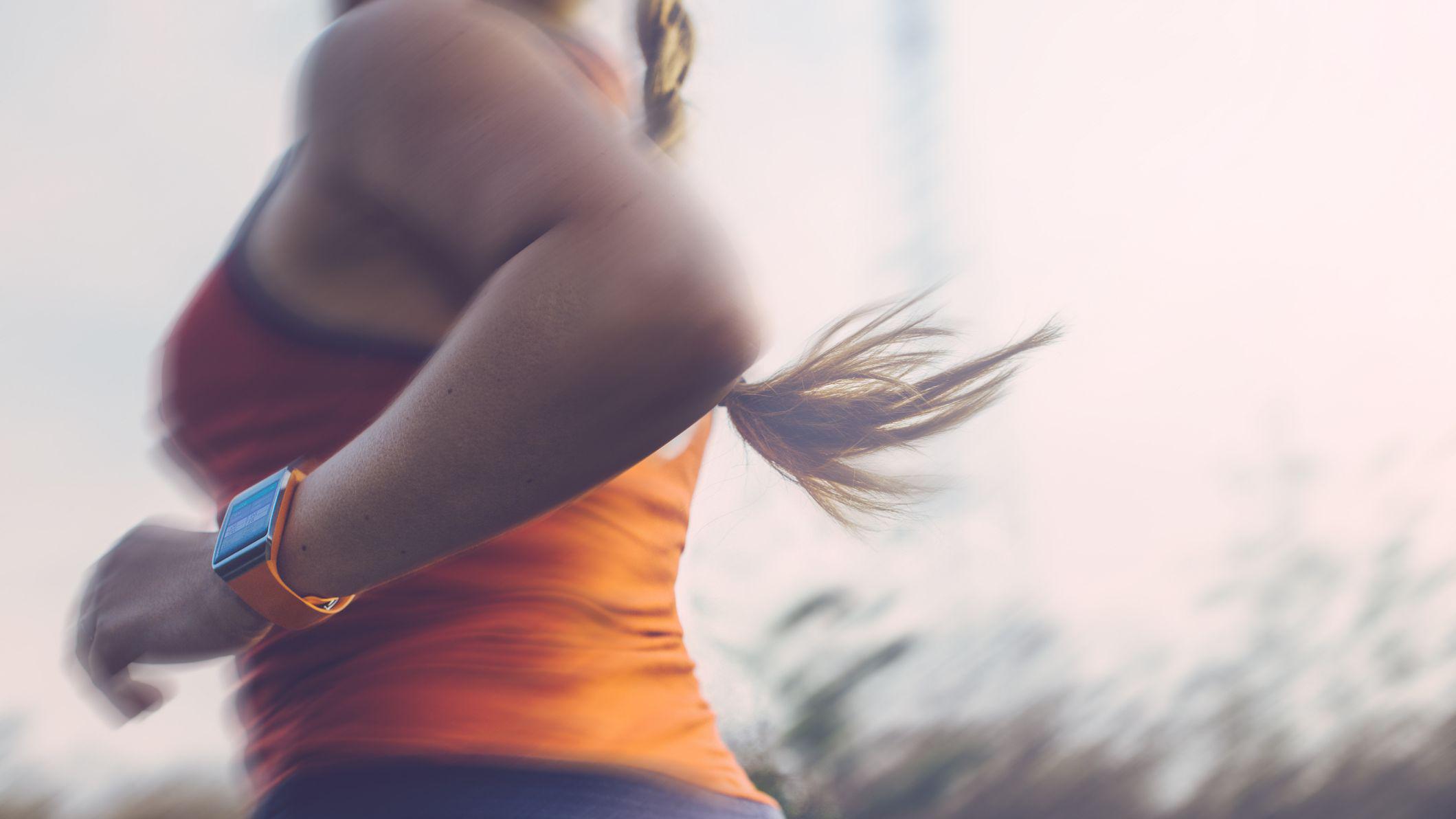 Una mujer corriendo en un parque con una camiseta naranja