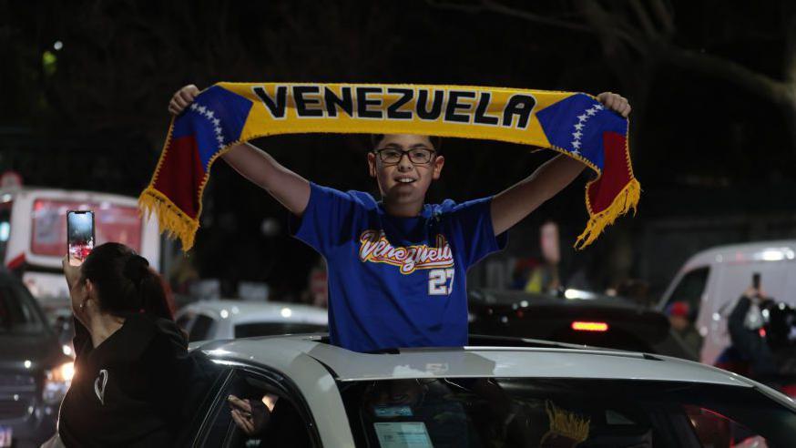 Un niño en un auto con un cartel que dice "Venezuela" durante las manifestaciones en Buenos Aires