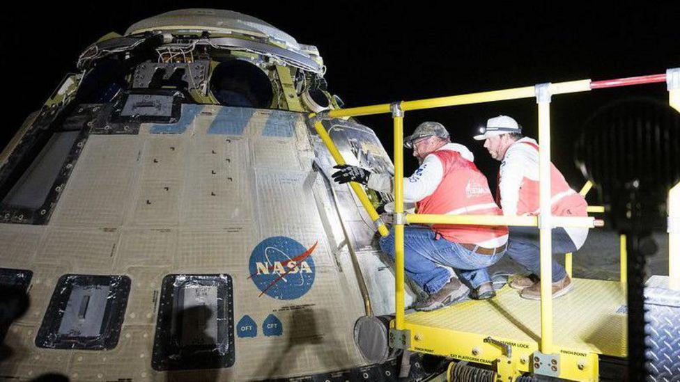 Dos trabajadores de la NASA inspeccionan la nave