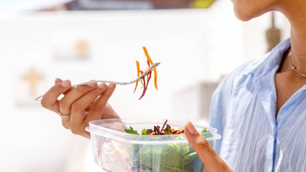 Joven comiendo una ensalada de un tupper