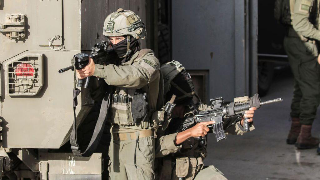 Un soldado israelí enmascarado apuntando con su rifle