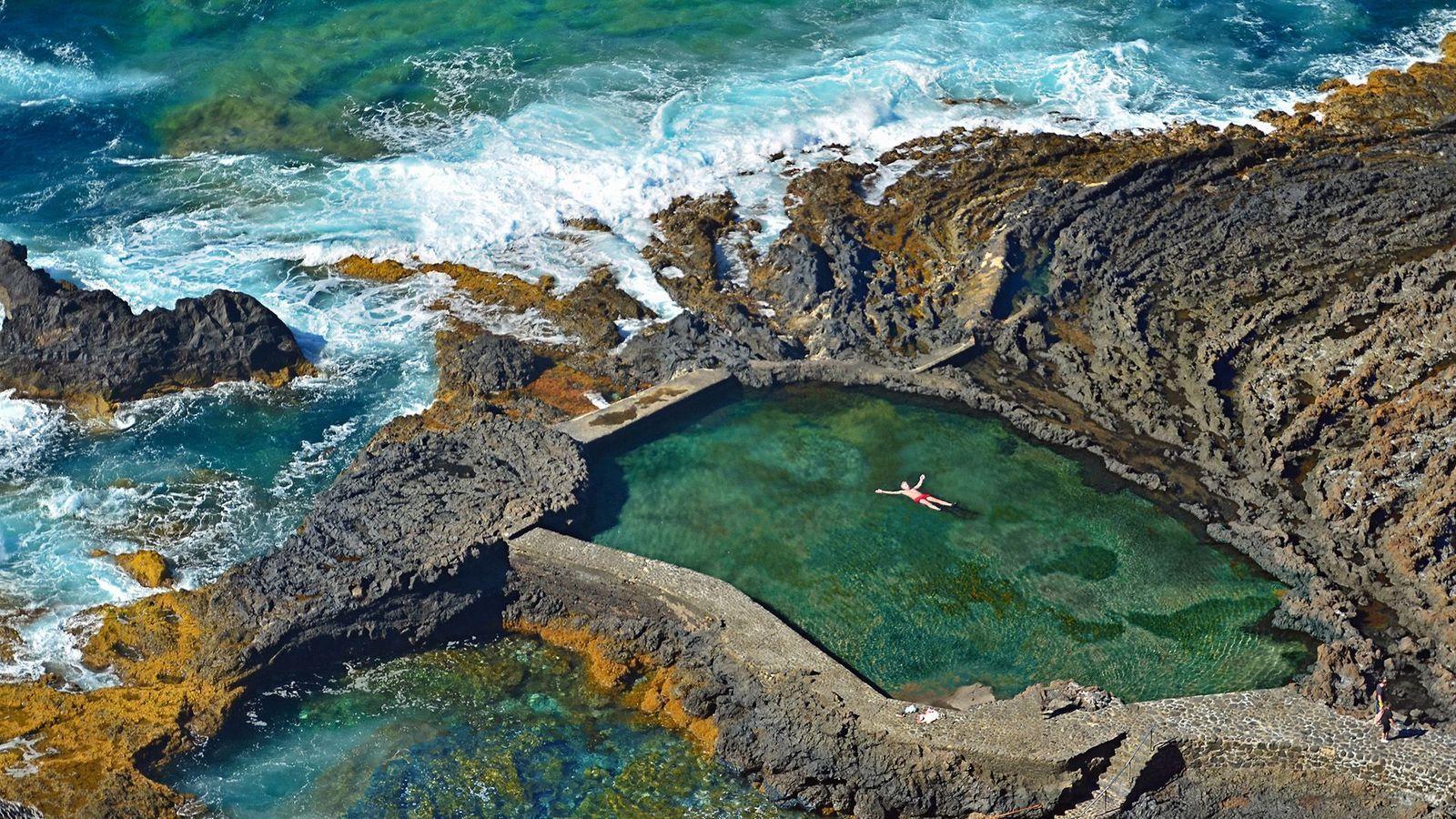 Hombre nadando en una piscina natural. 