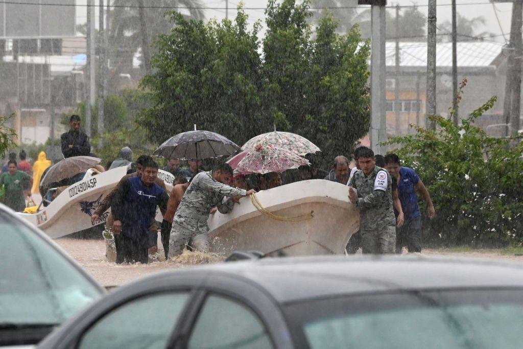 Miembros de la guardia nacional y agentes de policía ayudan a la gente en una calle inundada tras el paso del huracán John en Acapulco, México, el 26 de septiembre de 2024. 