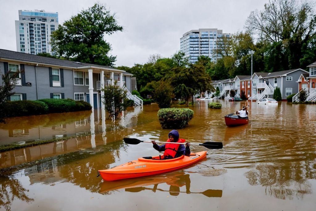 Dos personas atraviesan una calle residencial en kayak 