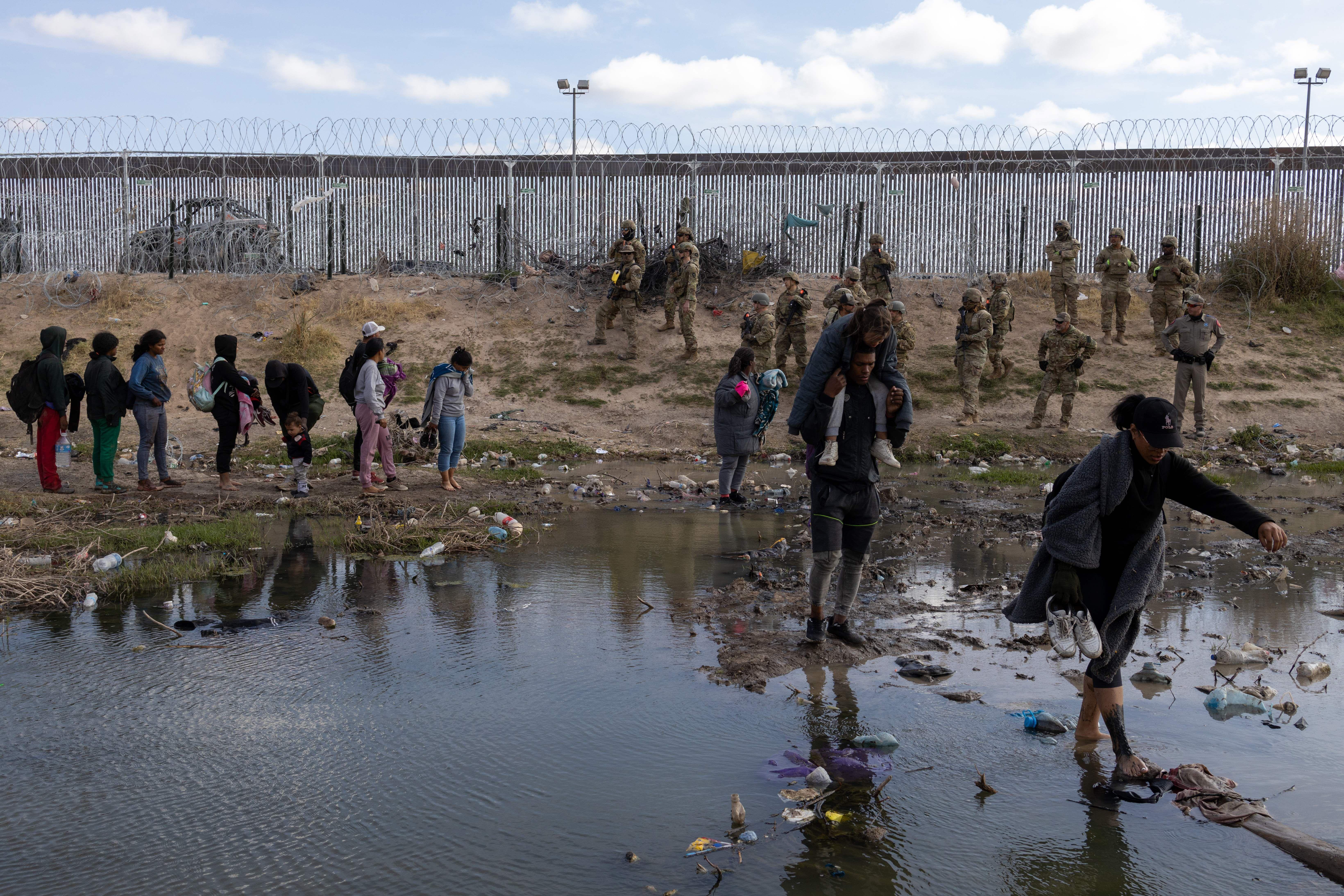 Migrantes en la frontera entre México y Estados Unidos observados por miembros de la Guardia Nacional de Texas