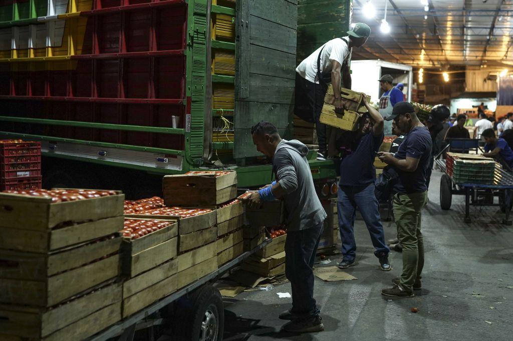 Varios hombres descargan cajas de un camión en La Tiendona, San Salvador, El Salvador, el 13 de febrero de 2023.