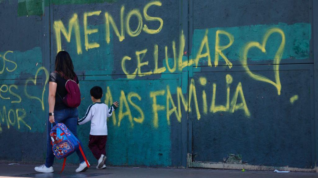 Una pintada en Chile que dice "Menos celular, más familia".