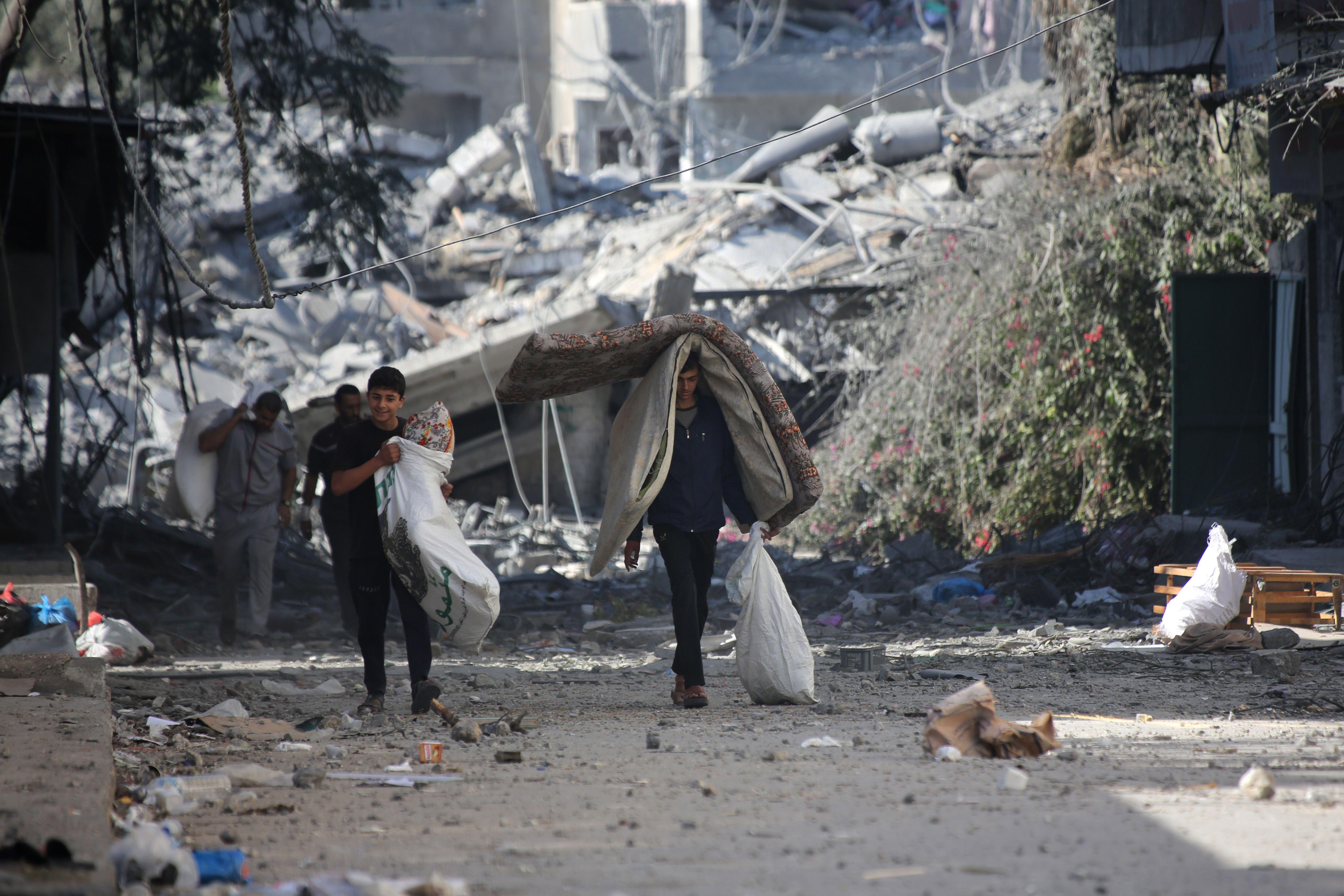 Palestinos desplazados con escombros detrás luego de un bombardeo israelí en Gaza. 