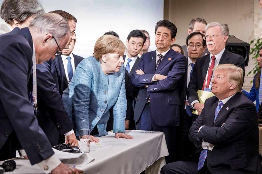 Donald Trump sentado durante una cumbre del G7en 2018 en Canadá, rodeado de Ángela Merkel de Alemania,Theresa May de Reino Unido, Emmanuel Macron de Francia, Shinzo Abe de Japón y el consejero de Seguridad de EE.UU. John Bolton