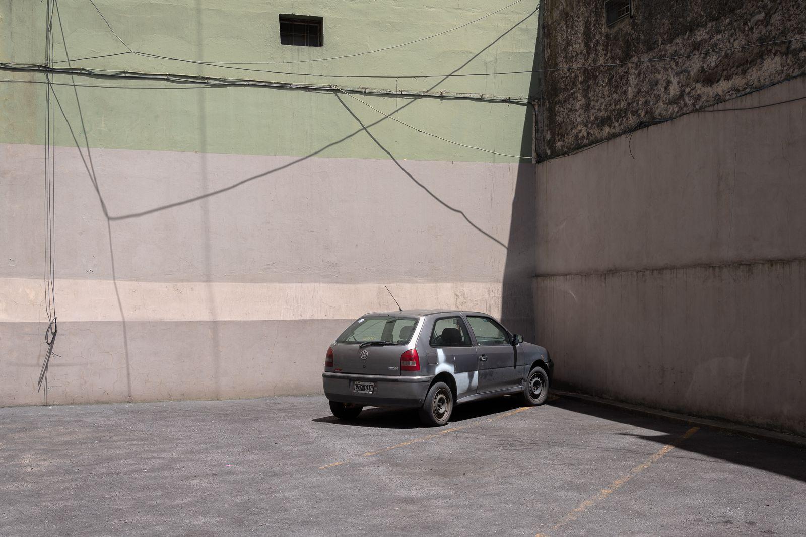 Un automóvil gris estacionado frente a un gran muro