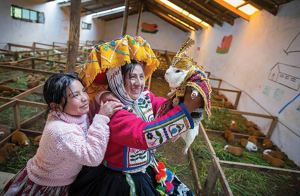 Una mamá junto a su niña sosteniendo un cuye