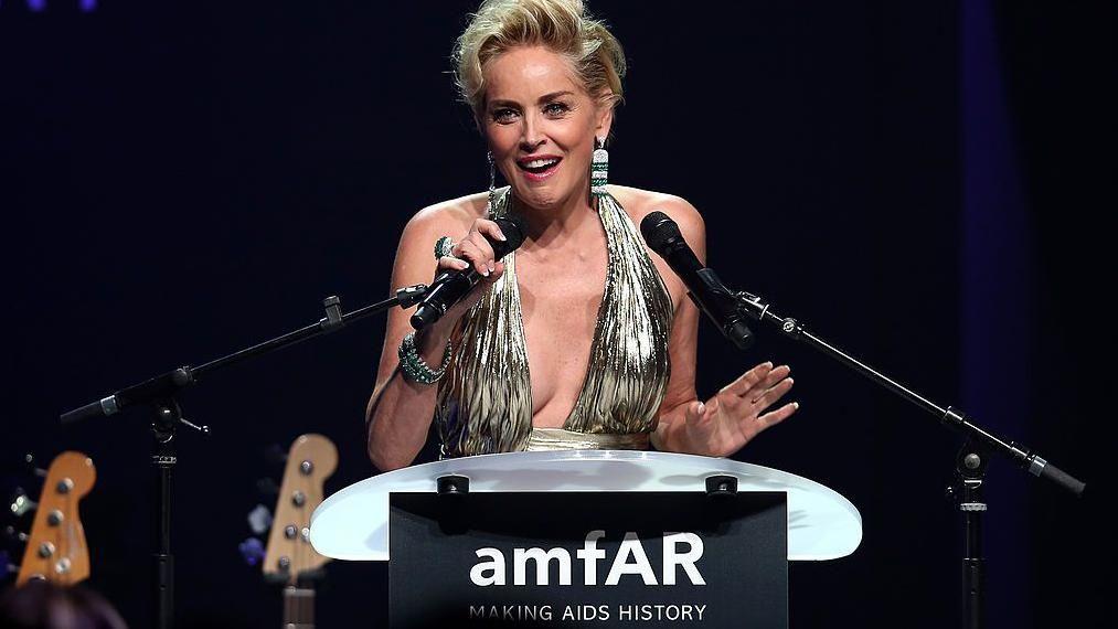 Sharon Stone, con un vestido plateado y hablando a través de un micrófono, en la Gala del Cine Contra el SIDA en Francia en 2014