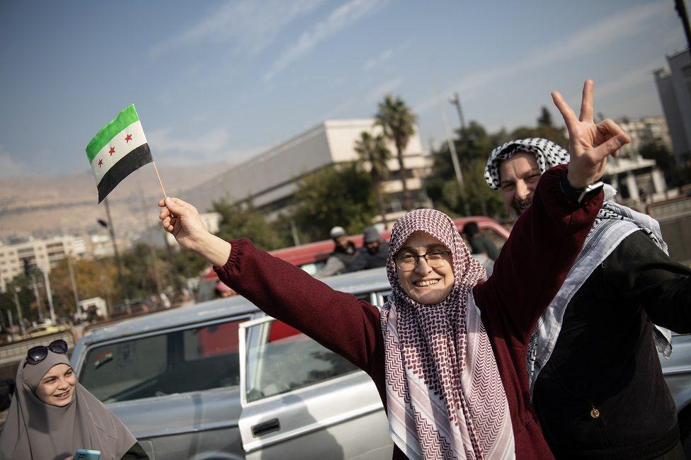 Una mujer con la bandera siria celebrando