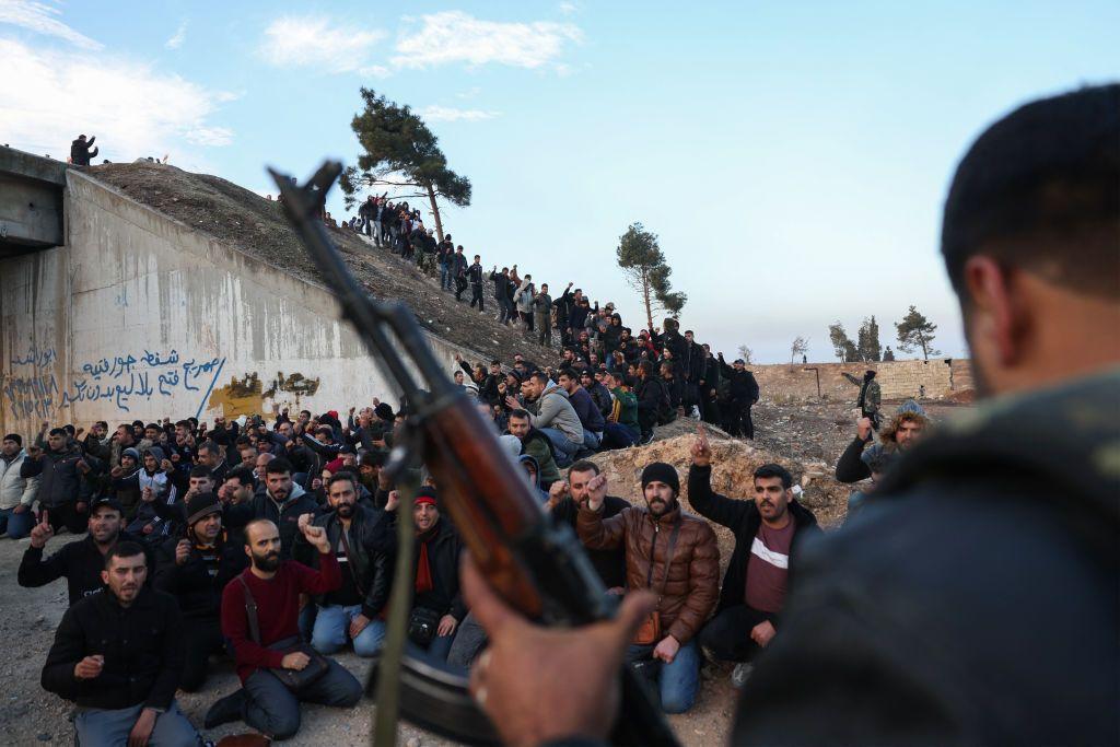 Un rebelde sirio armado vigila a soldados y paramilitares pro Al Assad.