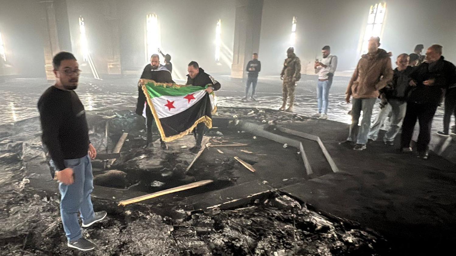 Rebeldes despliegan la bandera de la revolución siria dentro del mausoleo de Hafez al Assad.