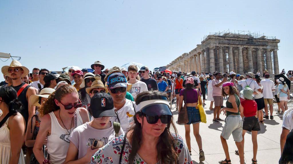 En la cima de la antigua colina de la Acrópolis, los turistas visitan el templo del Partenón durante una ola de calor el 20 de julio de 2023 en Atenas, Grecia.