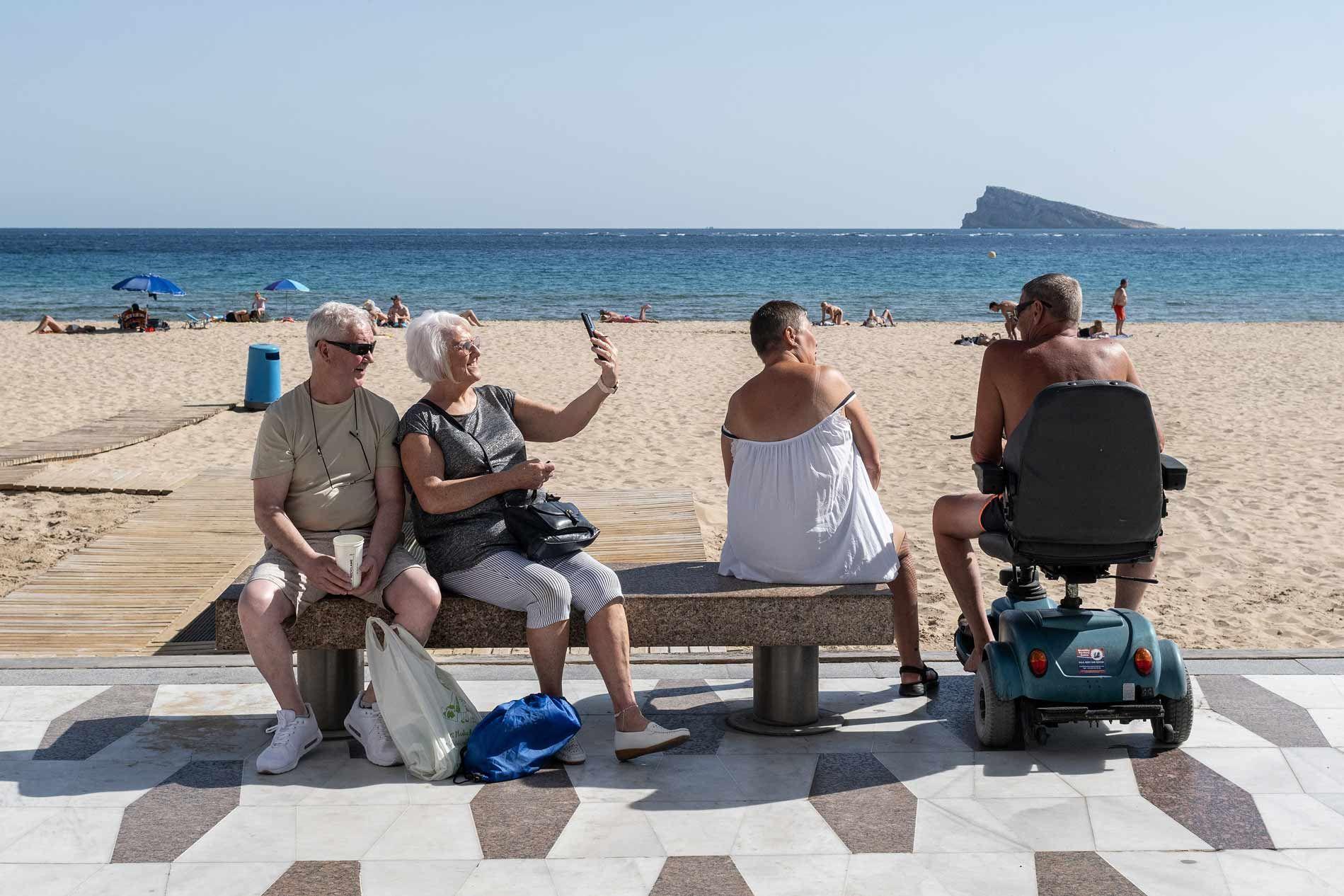 Cuatro personas sentadas en la costanera de Benidorm, España.