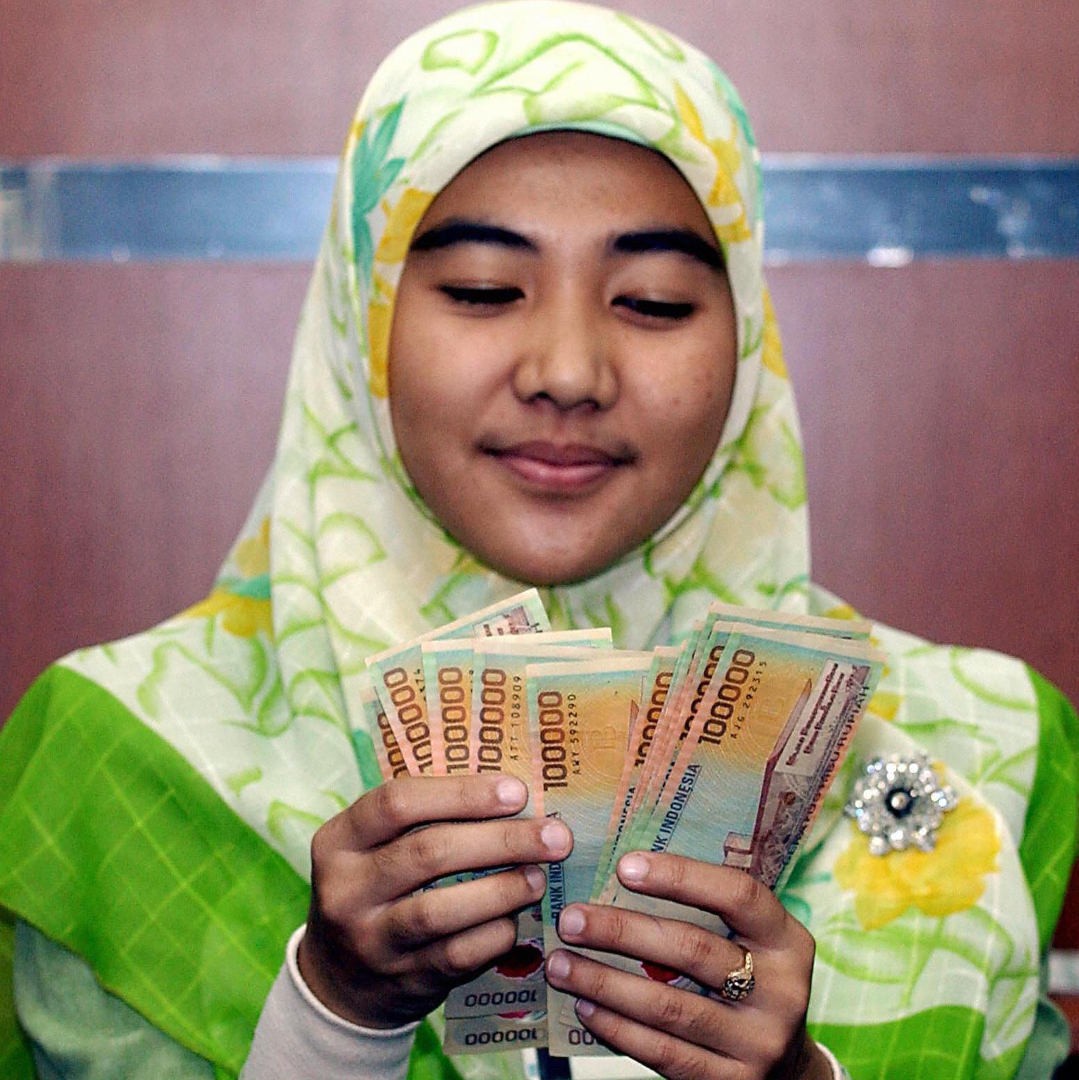 Una mujer con ropa tradicional de los países islámicos cuenta billetes.