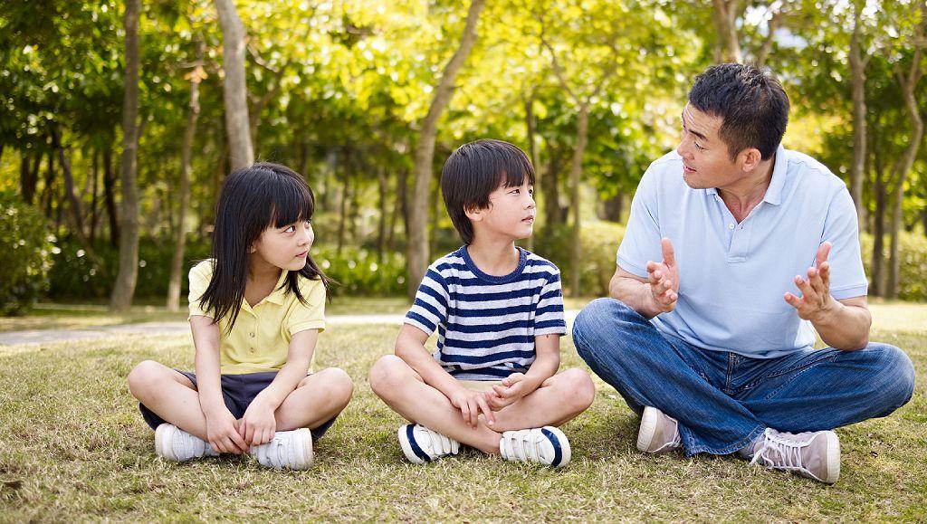 Un hombre hablando con dos niños en un parque